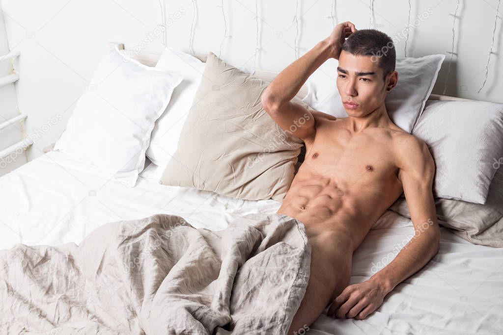 Young handsome man rest in bed. Sexy naked guy is resting