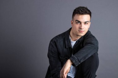 Stüdyoda poz veren ciddi bir genç.