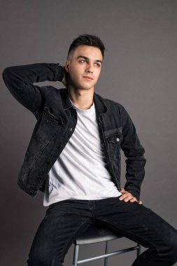 Stüdyoda poz veren ciddi bir genç.