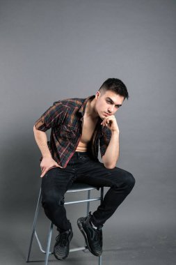 Stüdyoda poz veren ciddi bir genç.