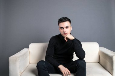 Stüdyoda poz veren ciddi bir genç.