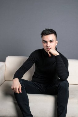 Stüdyoda poz veren ciddi bir genç. Gri arkaplan