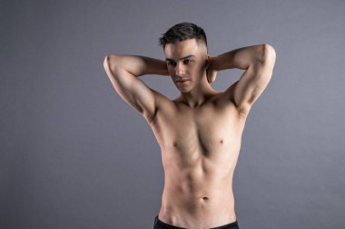 Stüdyoda poz veren seksi genç adam. Gri arkaplan