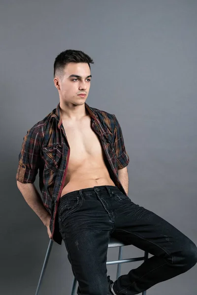 Young serious man posing in studio. Gray background — Stock Photo, Image