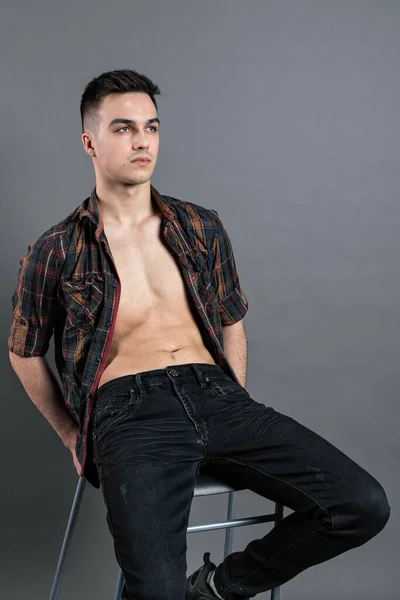 Young serious man posing in studio. Gray background — Stock Photo, Image