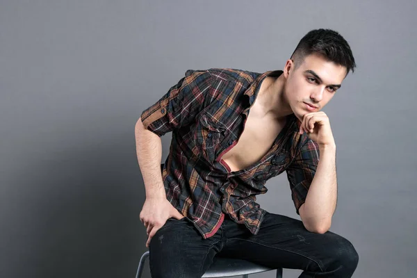 Young serious man posing in studio. Gray background — Stock Photo, Image
