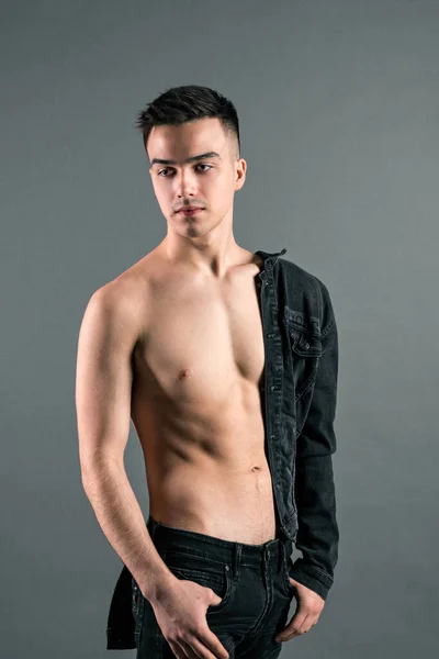 Sexy junger Mann posiert im Studio. Grauer Hintergrund — Stockfoto