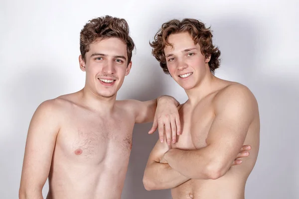 Two young sexy guys hugs on a white background