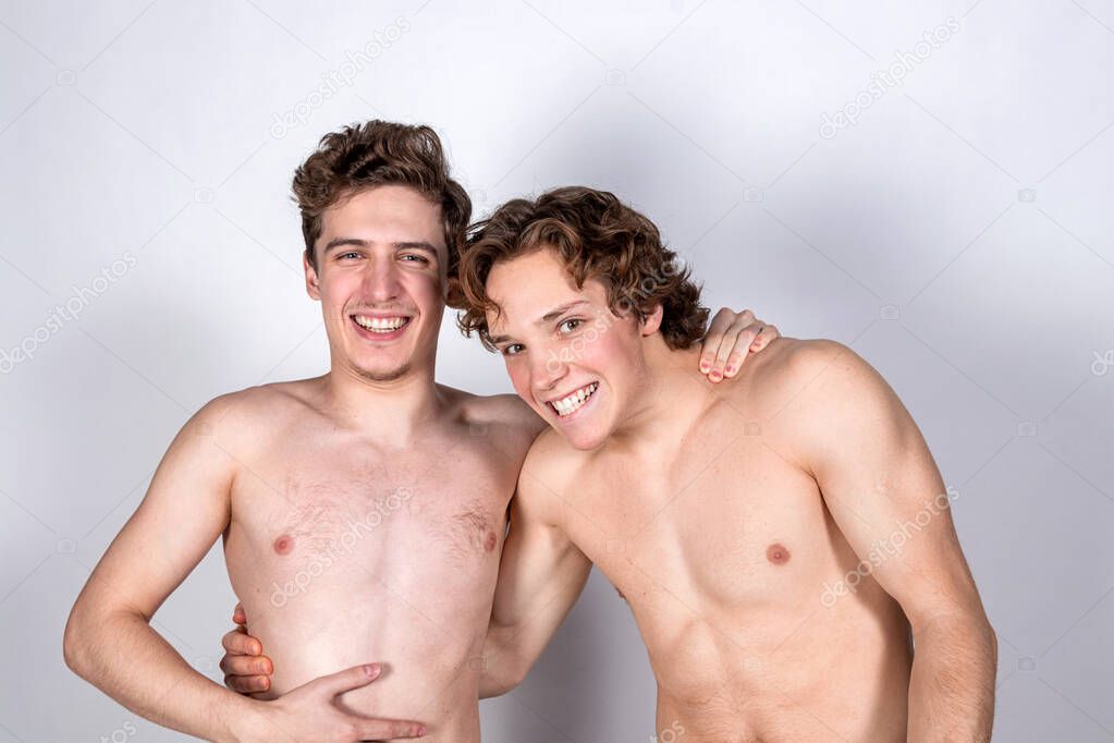 Two young sexy guys hugs on a white background