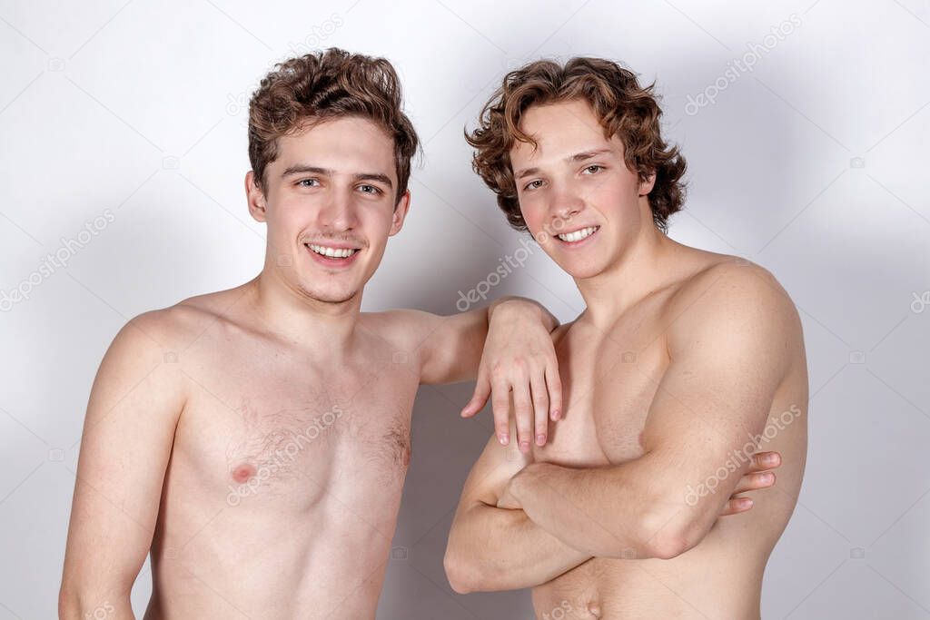 Two young sexy guys hugs on a white background
