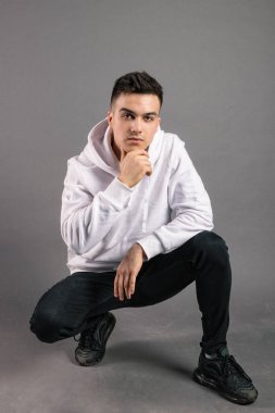 Stüdyoda poz veren ciddi bir genç.