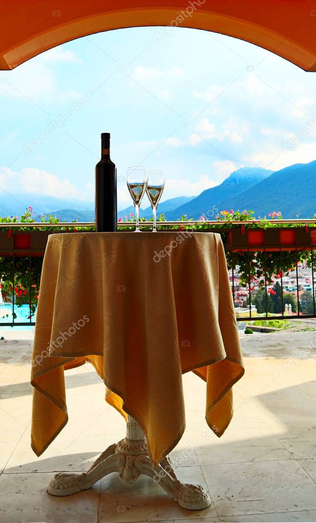 A bottle of wine, two glasses, and Lugano as background