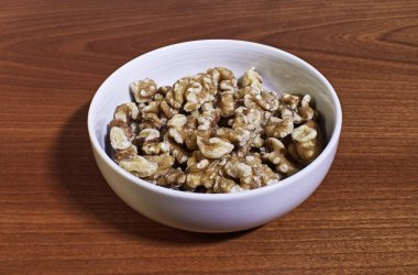 Tahta masadaki seramik kasede cevizler.