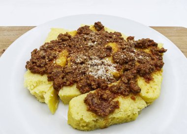 Bolonez soslu polenta ve ahşap masada parmesan peyniri.
