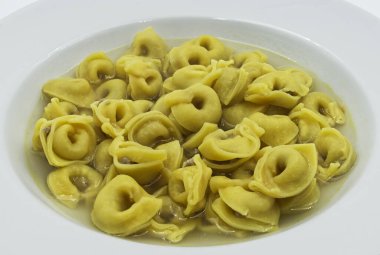 Brodo 'daki Tortellini (çorba) beyazı izole etti. Geleneksel İtalyan makarnası