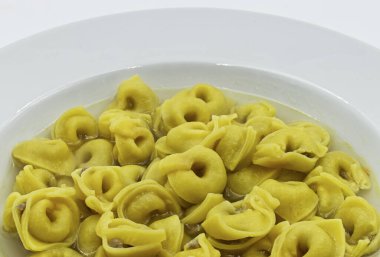 Brodo 'daki Tortellini (çorba) beyazı izole etti. Geleneksel İtalyan makarnası