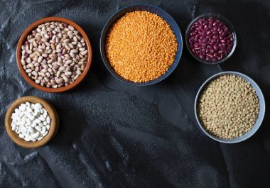 Baklagil çeşitleri: fasulye ve mercimek. Çiğ sağlıklı yemek. Sebze proteini. Karanlık arka plan. Üst Manzara. Metin için boşluk