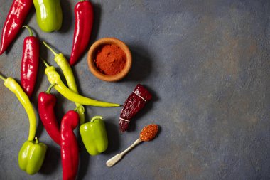 Biberler. Farklı biber çeşitleri. Kırmızı biber, yeşil biber, acı biber, kurutulmuş kırmızı biber, kırmızı biber tozu, biber, baharat. Üst Manzara. Karanlık arka plan. Metin için boşluk
