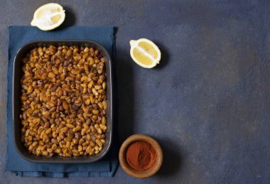 Balkanlarda pişmiş fasulye. Sırp, Karadağ, Bosna, Hırvat ve Sloven mutfağı. Fırında fasulye, limon, kırmızı biber tozu. Karanlık arka plan. Üst Manzara. Metin için boşluk