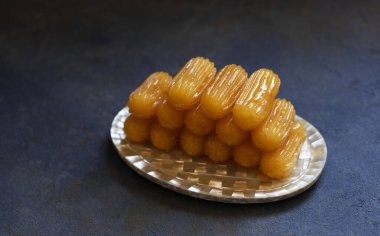 Tulumba adında geleneksel bir tatlı. Türk mutfağı. Balkan mutfağı. Levantine mutfağı. Mavi bir arka planda, eski bir doğu plakasında servis ediliyor.