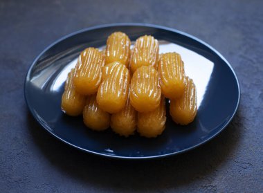 Tulumba adında geleneksel bir tatlı. Türk mutfağı. Balkan mutfağı. Levantine mutfağı. Mavi bir arka planda, mavi bir tabakta servis edilir.