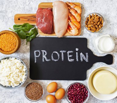 Yüksek seviyede protein içeren çeşitli ürünler var. Sağlıklı Protein kaynağı. Kas geliştirmek için gıdalar. Et, deniz ürünleri, peynir, süt, fındık, bakla, tohum, yumurta, sebze. Hafif arkaplan. Üst görünüm