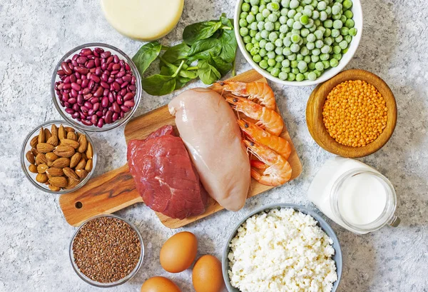 Assortment of Products with high level of protein. Healthy Protein Source. Foods for muscles building. Meat, seafood, cheese, milk, nuts, legumes, seeds, eggs, vegetables. Light background. Top view