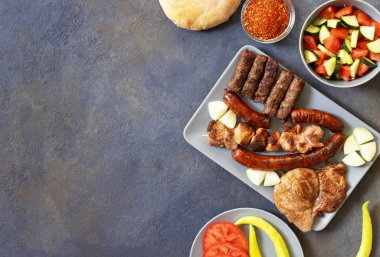 Geleneksel Sırp ve Balkan usulü ızgara mesano meso adı verilen et. Balkan barbeküsü (rostilj) Sırp salatası, acı biber, ekmek, domates, soğan ve kırmızı biber tozuyla servis edildi. Yakın plan.