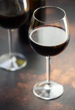 Gözlüklü kırmızı şarap, yakın plan, seçici odaklanma. Masada bir şişe kırmızı şarap ve iki bardak..