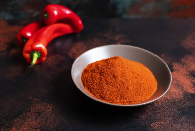 Koyu arkaplanda bir tabakta kırmızı biber tozu. Parlak renkler. Seçici odaklanma. Yakın plan.