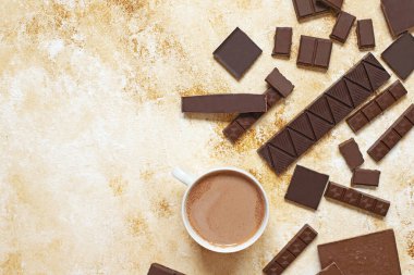 Hafif mermer arka planda bir fincan kakao. Çikolata ve kakao tozunun değişik çeşitleri. Üst manzara, düz yatış. Metin için boşluk.