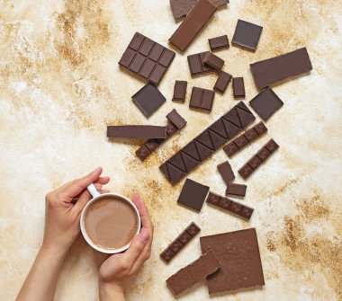 Hafif mermer arka planda bir fincan kakao. Çikolata ve kakao tozunun değişik çeşitleri. Üst manzara, düz yatış. Metin için boşluk.