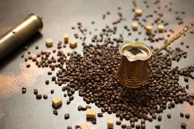 Türk kahvesi kavramı. Bakır kahve demliği (Cezve), antika kahve öğütücüsü, fincan, kahve çekirdeği ve koyu renkli arka planda şeker. 