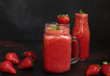 Kavanozda buzlu çilekli meyve püresi ve çilek. Ferahlatıcı bir yaz içkisi. Yakın çekim görüntüsü. Boşluğu kopyala