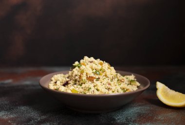 Geleneksel kuskus, içinde sebzeler ve otlar var. Limon. Levantine vejetaryen salatası. Lübnanlı, Arap mutfağı. Yakın plan..
