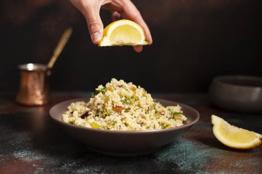 Geleneksel kuskus, içinde sebzeler ve otlar var. Limon. Levantine vejetaryen salatası. Lübnanlı, Arap mutfağı. Yakın plan..