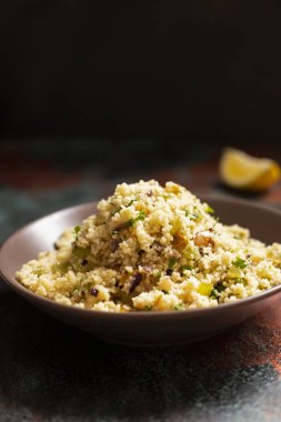 Geleneksel kuskus, içinde sebzeler ve otlar var. Limon. Levantine vejetaryen salatası. Lübnanlı, Arap mutfağı. Yakın plan..