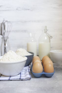 Hamur için malzemeler, beyaz arka planda pişirme malzemeleri. Yumurta, süt, un ve tel çırpıcı. Ön manzara. Pişirme konsepti. Metin için boşluk