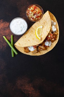Geleneksel Meksika fajitaları, tavuk ve sebzeli, beyaz ve kırmızı soslu tortilla, limon ve taze yeşil soğanlı. Yakın plan..