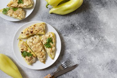 Peynirle doldurulmuş kavrulmuş biber ve beyaz tabakta otlar. Balkan mutfağının karakteristik bir yemeği. Sırp mutfağı. Gri arkaplan, üst görünüm, kopyalama alanı