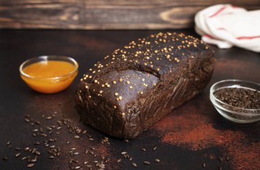 Koyu ahşap arka planda tam tahıllı çavdar ekmeği, bal ve malt. Taze pişmiş ev yapımı ekmek. Yakın çekim, seçici odaklanma