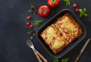 Domates soslu ve tavuklu ev yapımı İtalyan lazanyası. Domates ve fesleğenle servis edilmiş. İki porsiyon. Karanlık arka plan. Üst Manzara. Boşluğu kopyala
