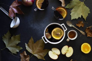 Beyaz kupa ve sıcak şarap. Sonbahar ve kış ılık alkolik içeceği. Sonbahar yaprakları, bal, elma, portakal, klasik yemekler. Sonbahar sıcacık havası. Düz, koyu arkaplan