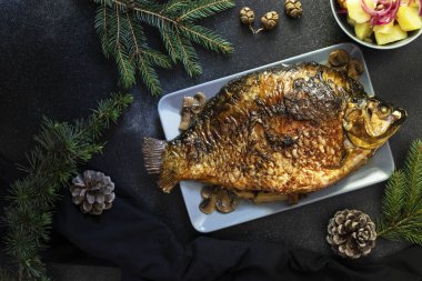 Noel sazanının tamamı mantarla pişirilmiş. Koyu bir arka planda patates salatasıyla servis edilmiş. Geleneksel Noel arifesi yemeği. Üst Manzara. Metin için boşluk