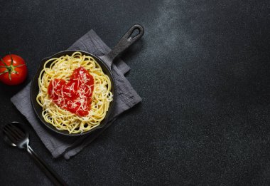 Kalp şeklinde domates soslu spagetti makarna, tavada servis edilir. Sevgililer Günü için akşam yemeği. Sevgiyle yemek. Üst görünüm, düz görünüm, siyah arkaplan