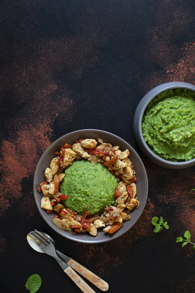 Mashed potatoes with green peas and corn served with chicken and vegetable stew. African cuisine, Kenyan cuisine, a traditional dish called mukimo. Top view, copy space