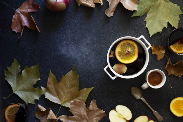 白マグカップにホットワイン 秋と冬の暖かいアルコール飲料 秋の葉 リンゴ オレンジ ヴィンテージ料理 秋の居心地の良い気分 フラットレイアウト 暗い背景 — ストック写真