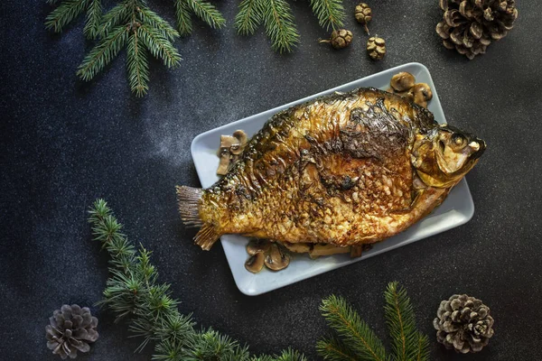 Christmas whole Carp baked with mushrooms. Served on a dark background with potato salad. Traditional Christmas Eve meal. Top view. Space for text