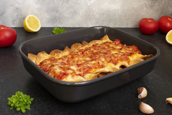 Mexican Enchiladas with chicken, vegetables, corn, beans and cheese. Served in a baking tray on a black table. Mexican food. Latin American cuisine. Gray background, close up, copy space — Stock Image Mexican Enchiladas Chicken Vegetables Corn Beans Cheese Served Baking Tray Royalty Free Stock Images