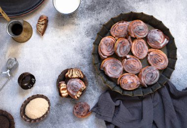 Tarçınlı rulo ya da kremalı tarçınlı klasik bir tabak, kahve, süt, esmer şeker. Ev yapımı geleneksel fırın tatlısı. Gri arkaplan, üst görünüm, kopyalama alanı